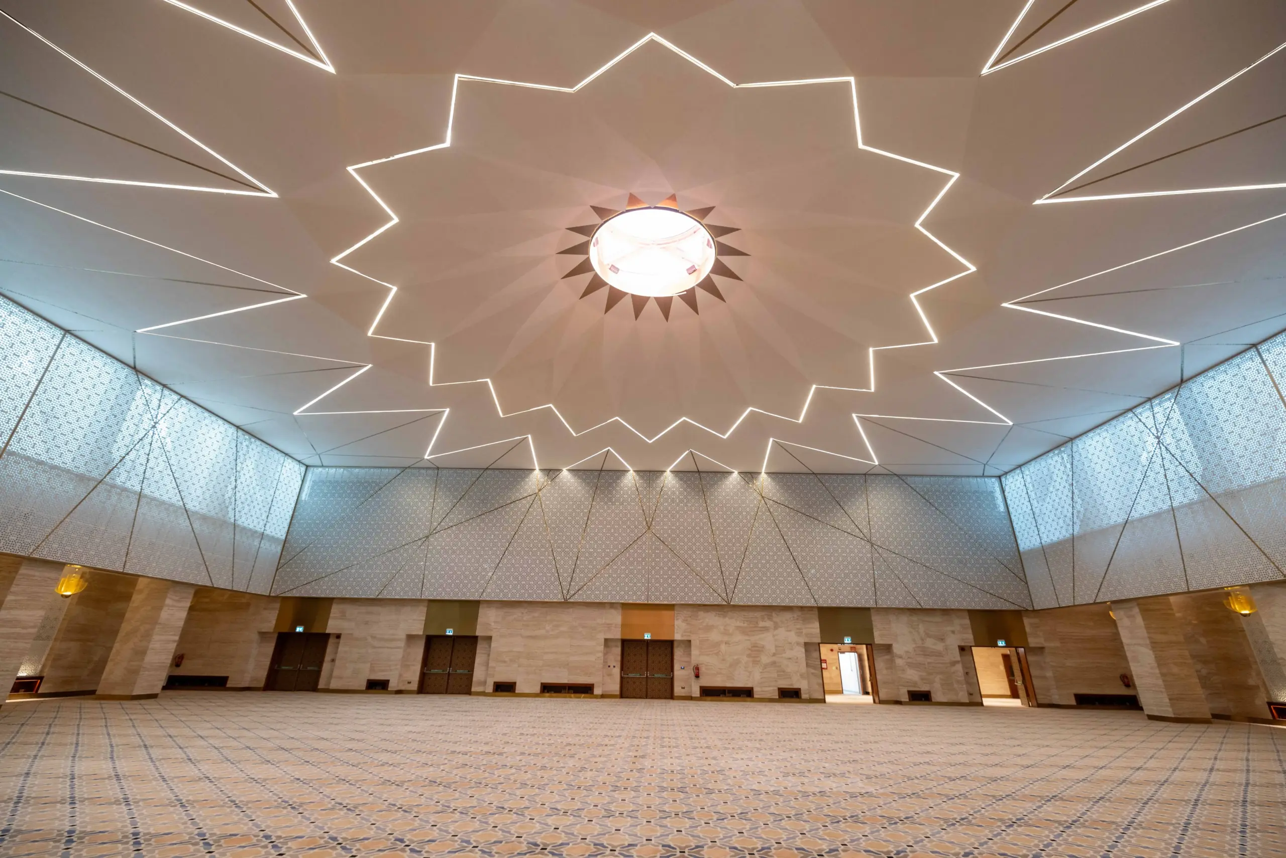 Interior hallway at Mosque Twenty-Seven with dark wood paneling, white walls, and a detailed white-and-gray Islamic geometric patterned floor