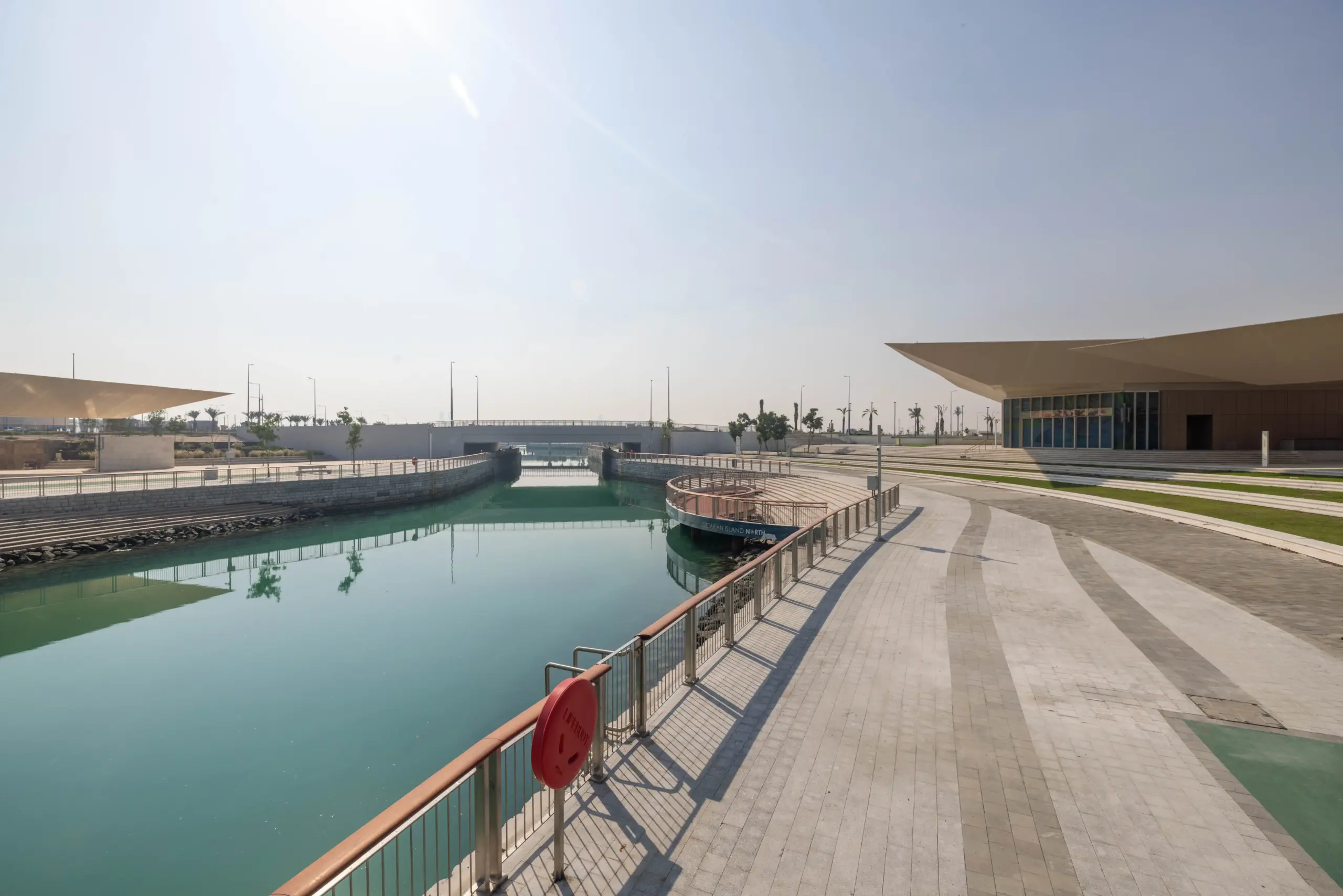 Retail and F&B plazas on Qetaifan Island North, showing modern angular buildings along the Majra Alsail canal with outdoor dining and pedestrian promenades