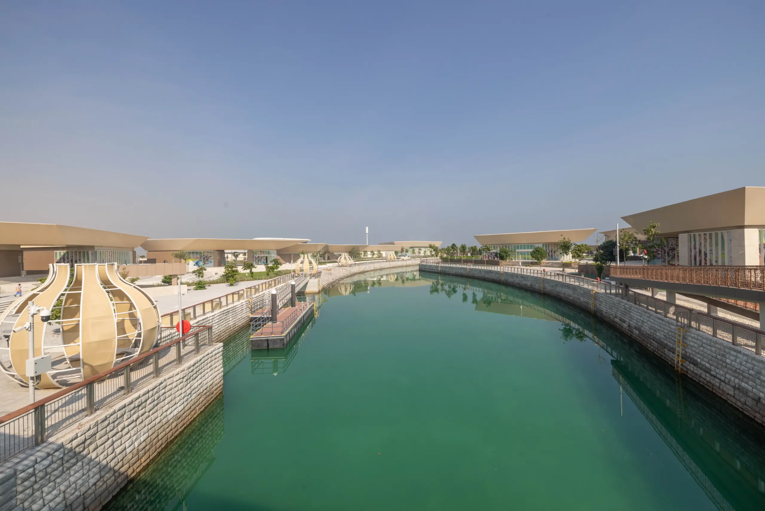 Trove East & West retail plazas on Qetaifan Island North, showing modern angular buildings along the Majra Alsail canal with outdoor dining and pedestrian promenades
