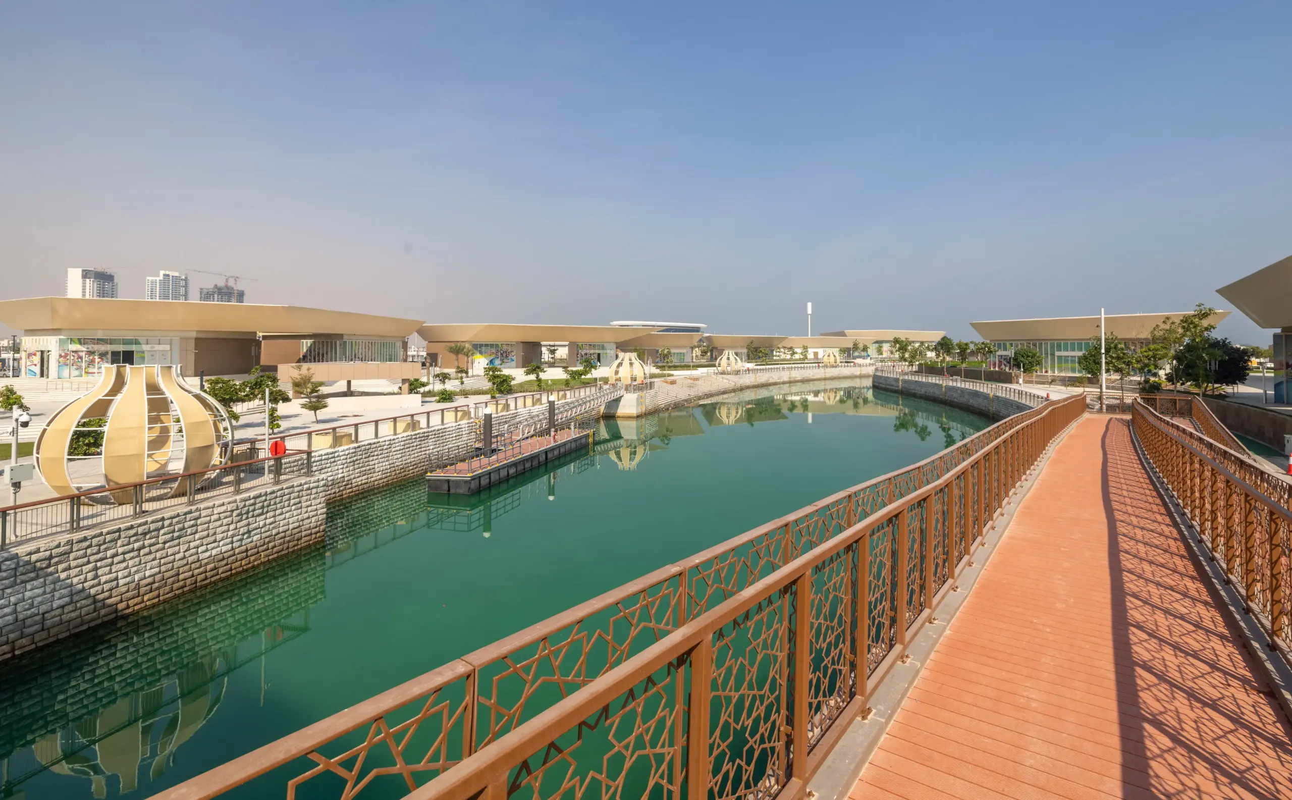Retail and F&B plazas on Qetaifan Island North, showing modern angular buildings along the Majra Alsail canal with outdoor dining and pedestrian promenades