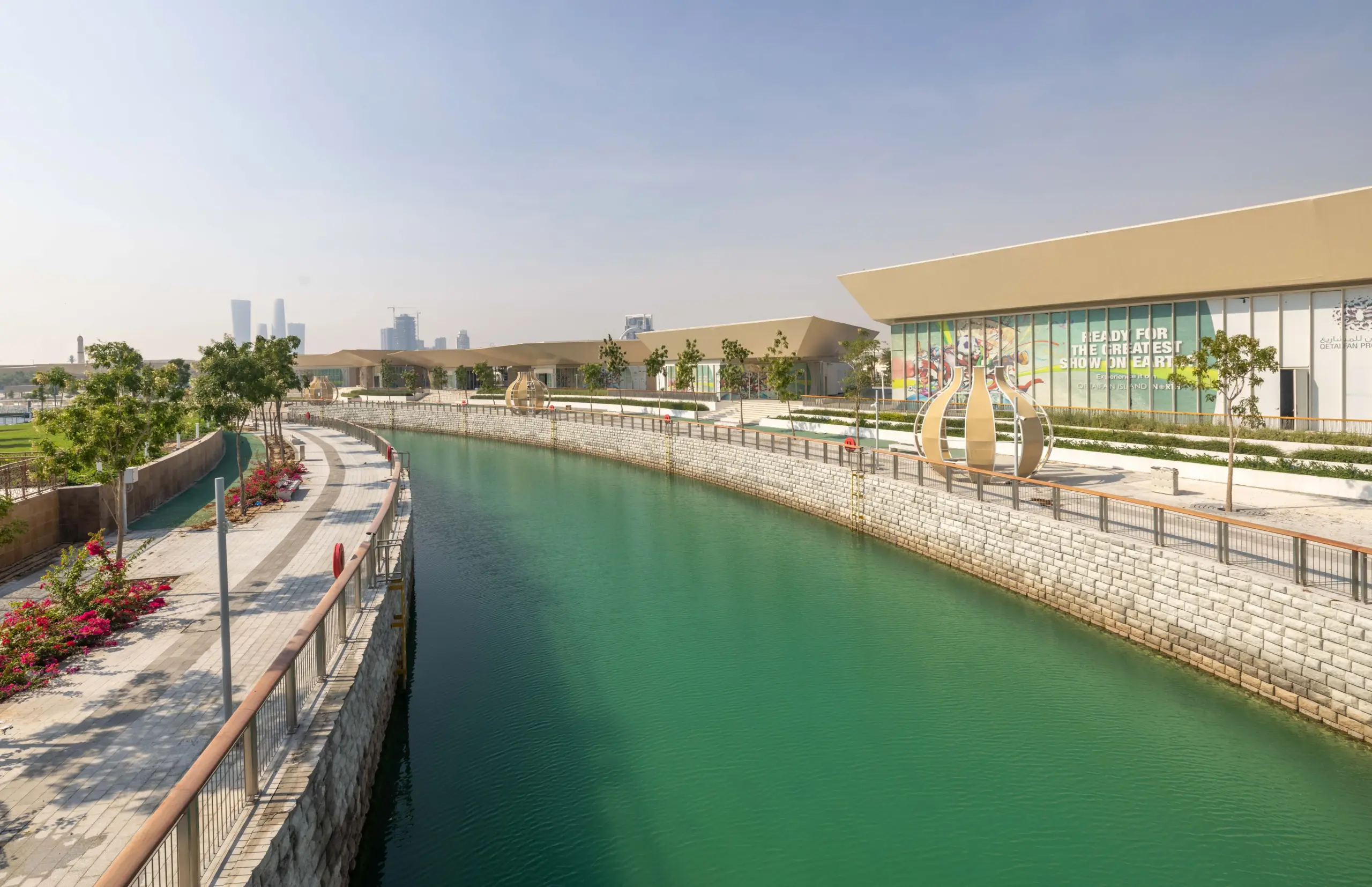 Trove East & West retail plazas on Qetaifan Island North, showing modern angular buildings along the Majra Alsail canal with outdoor dining and pedestrian promenades