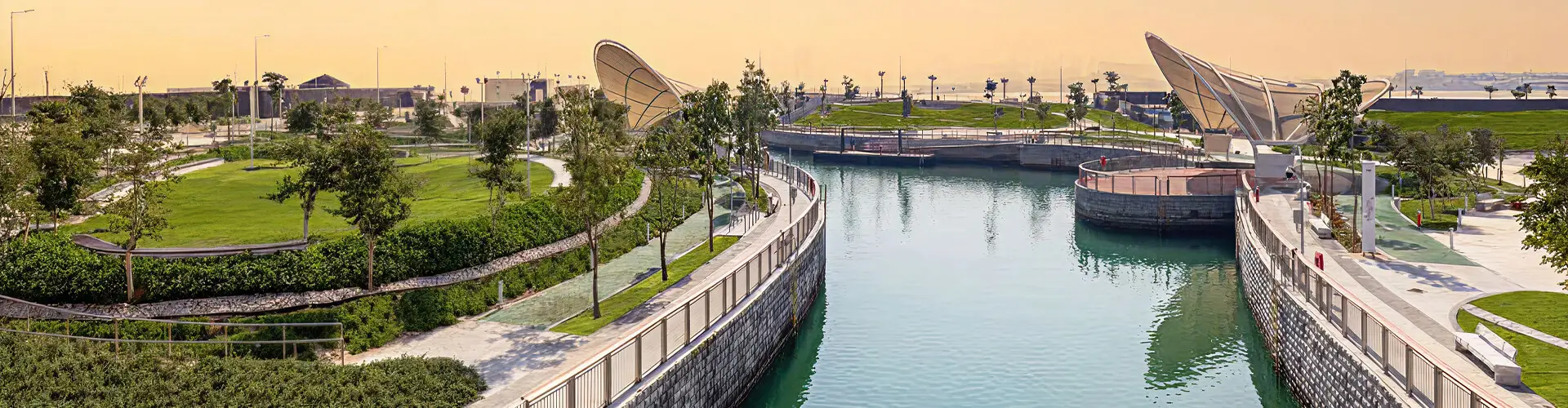 This is a panoramic photograph of a majra alsail park surrounding a man-made canal or waterway.